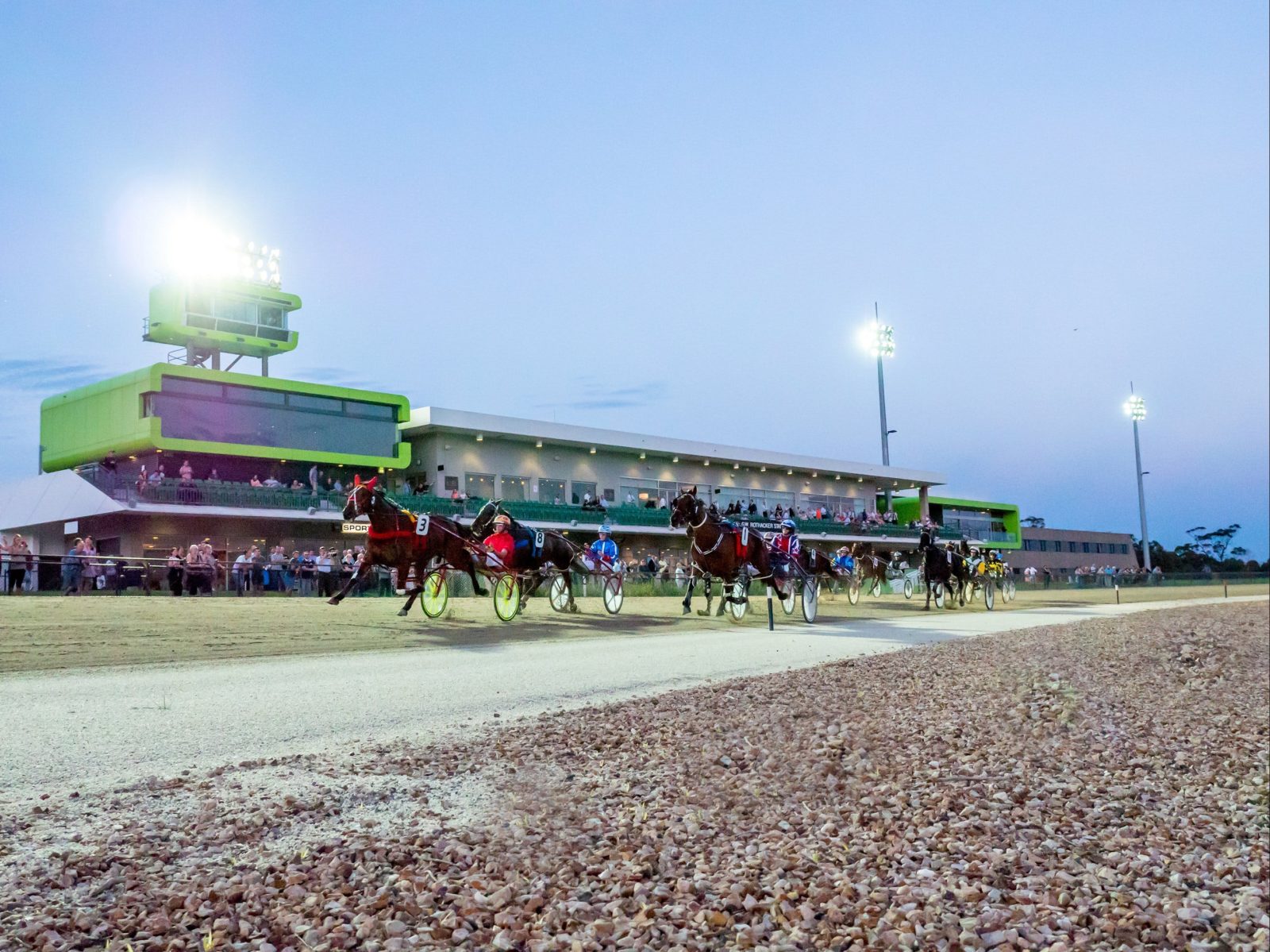 The Harness Racing Track with horses and drivers in a race, capturing the venue in the background.