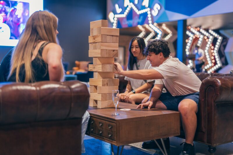 A group of three people playing giant jenga.