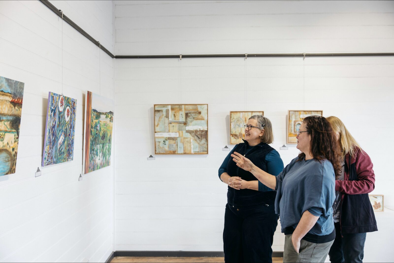 Three woman standing looking at a painting in our Kyneton Gallery