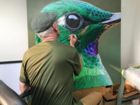 Artist Tony Pridham painting a huge picture of a hummingbird head