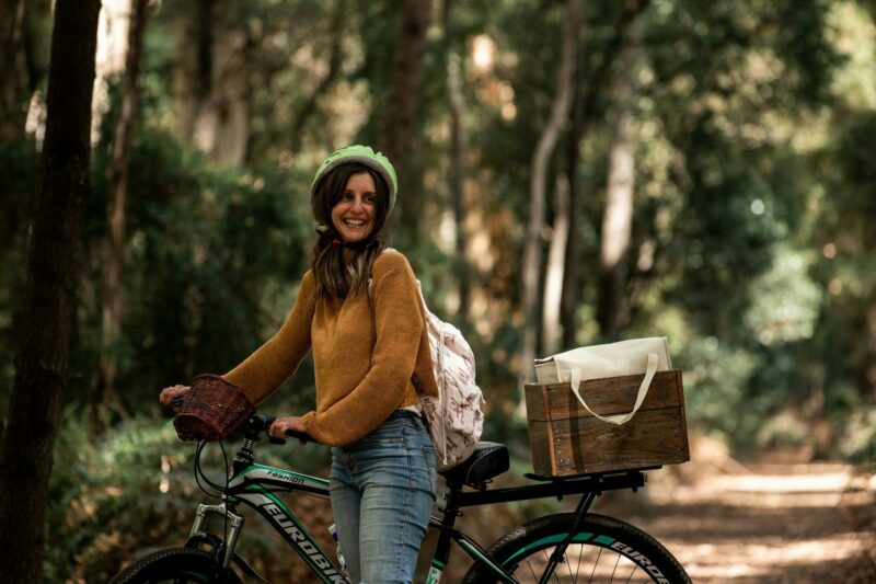 Lady standing next to a mountain bike on a rail trail surrounded by trees