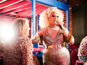 Drag Queen with a microphone with a woman looking on