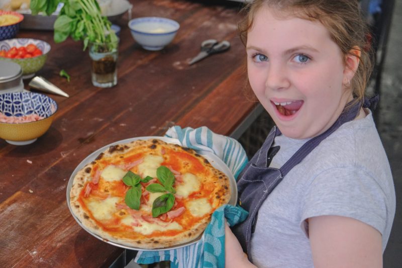 Girl proudly shows her recently made pizza
