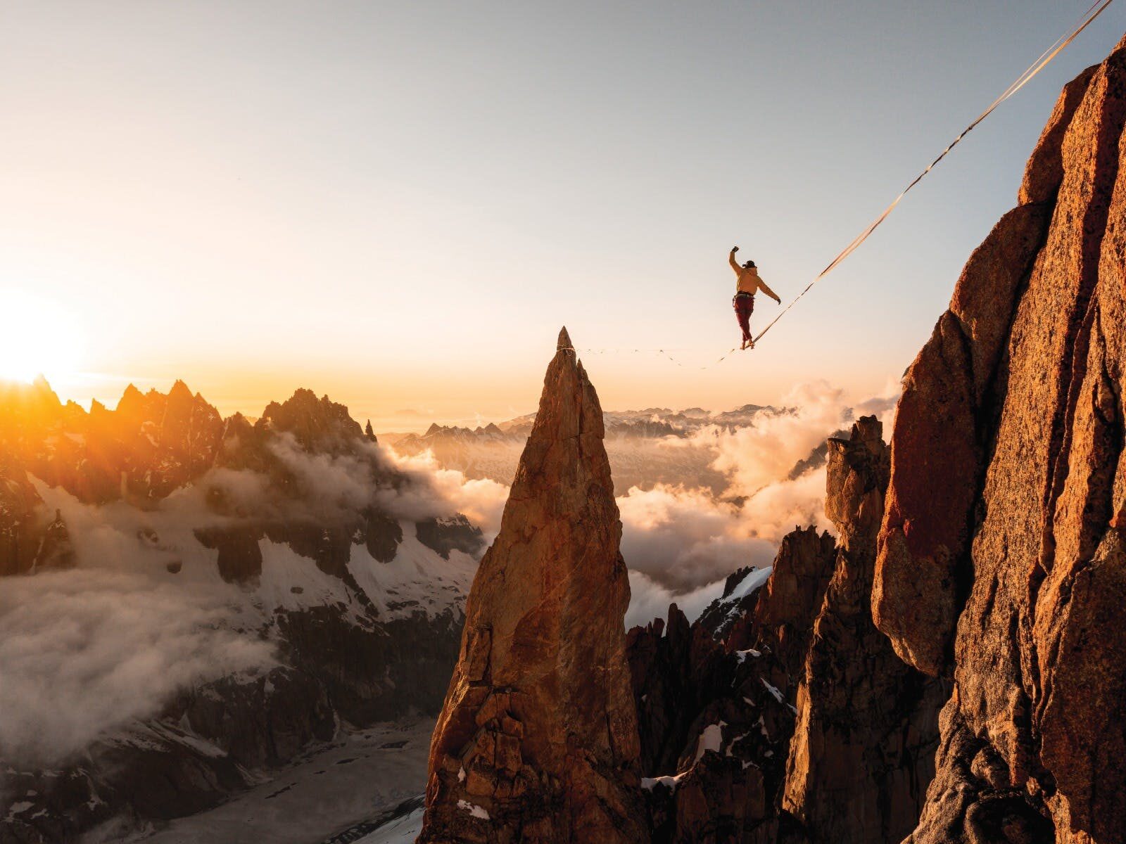 A man balancing on a tightrope in the mountains
