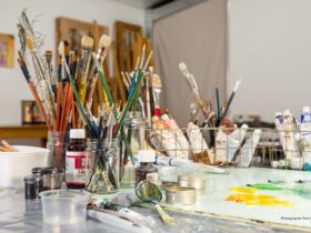 Photo of artist studio with jars of brushes, tubes of paint and squeezed out paint on work bench