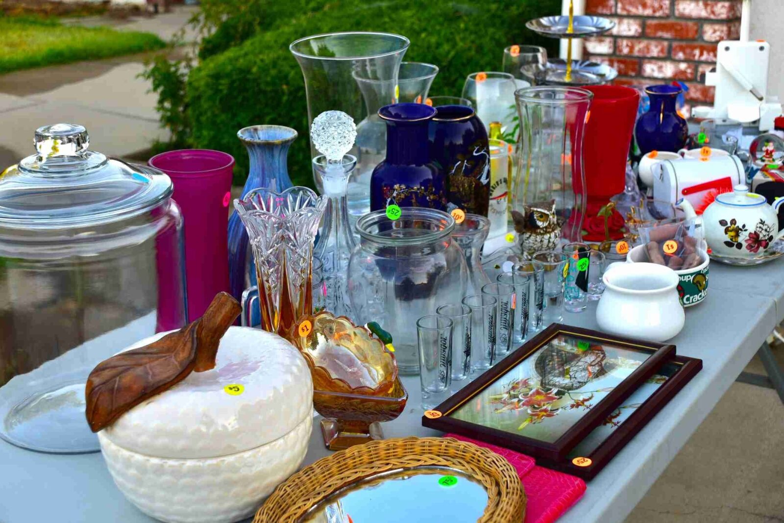 selection of items for sale at a garage sale includes glassware, picture frames