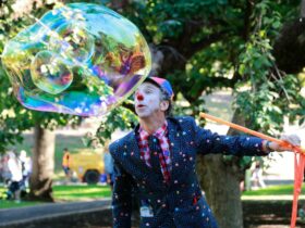 Tim Tim the entertainer with face paint is blowing a giant bubble