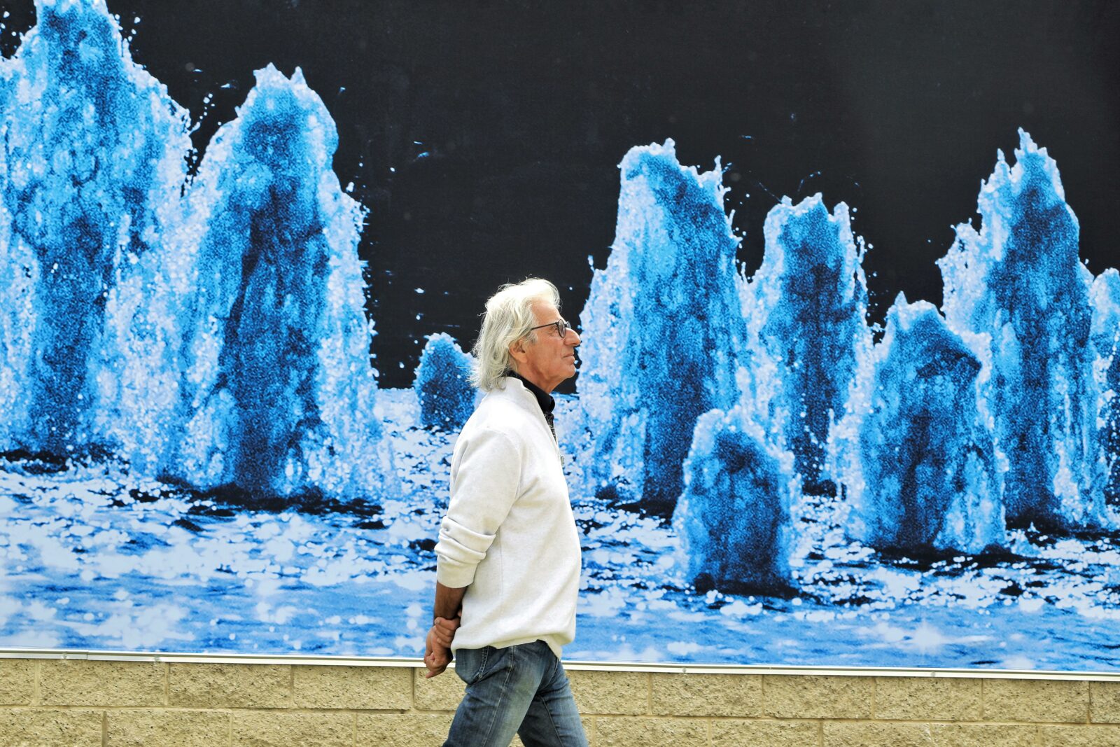 visitor walks in fron tof outdoor photohgraph affixed to wall of the museum