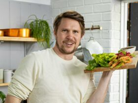 Simon Toohey in a kitchen holding a tray of vegetables