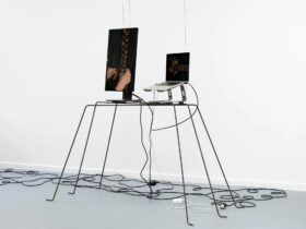 Pair of screens displaying hair being plated, displayed on a table with various wires