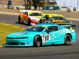 Three TA2 Muscle cars racing around a corner on a racetrack