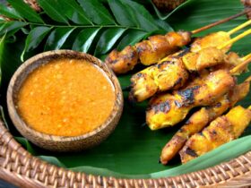 Chicken seasoned meat on banana leaf served with a bowl of peanut sauce. skewers with a