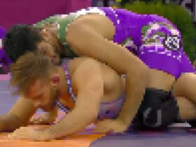 A pixelated image of 2 men wrestling in brightly coloured outfits.