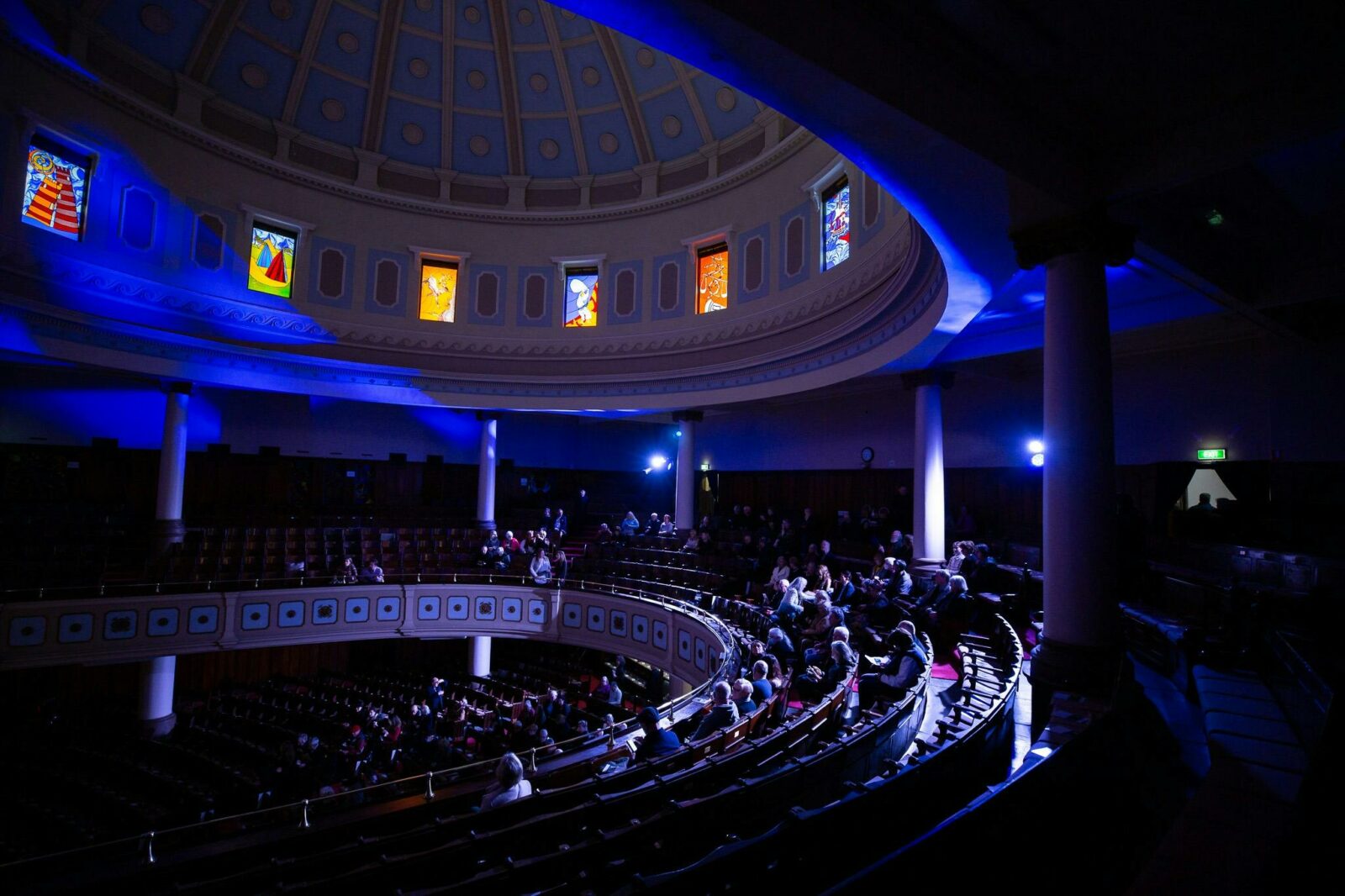 Image of a concert at Toorak Synagogue, Blue lighting, stained glass windows and a full house