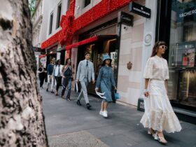 Models walking down a street in dresses and suits