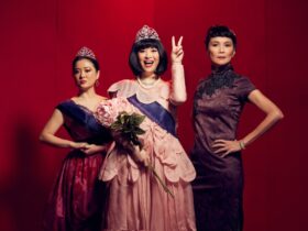 photo of the main cast members with the middle character wearing a sash, crown and holding a bouquet