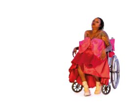 An actor on a wheelchair wearing a pink ball gown