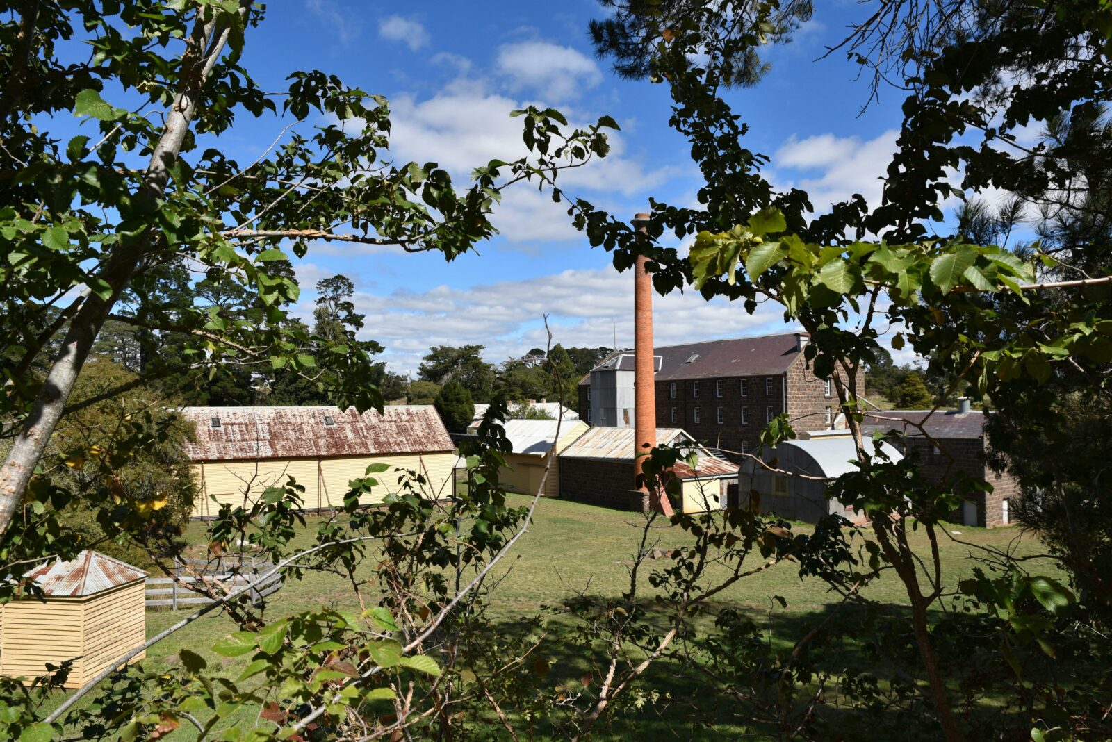 This photo show the bluestone mill, the large weatherboard granary and the tall red brick chimney