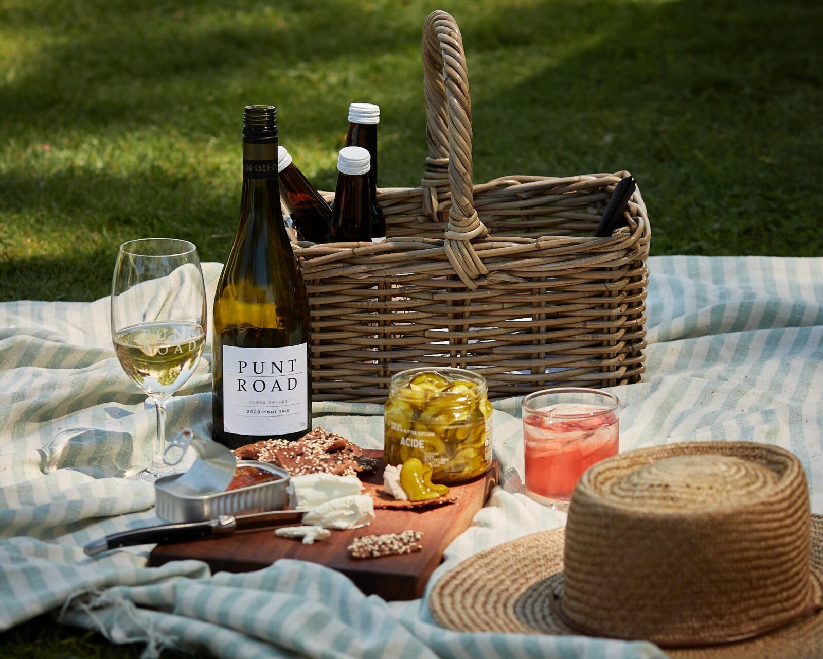 A blanket is laid out with a picnic and wine