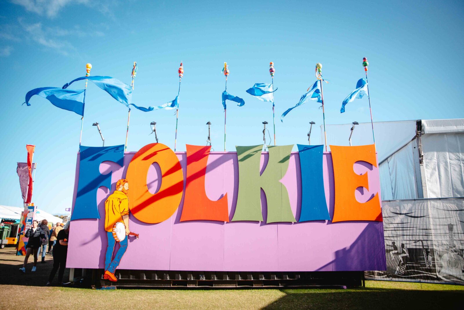 Artwork displaying the word "Folkie" and a man with a banjo inside the Port Fairy Folk Festival.