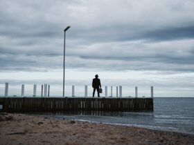 Silhouette of Man against cloudy sky, with suitcase on pier