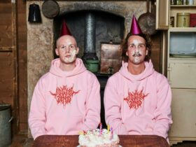 two males in pink jumpers with cake on their faces
