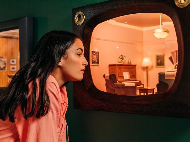 A girl looks at a diorama replica of a loungeroom