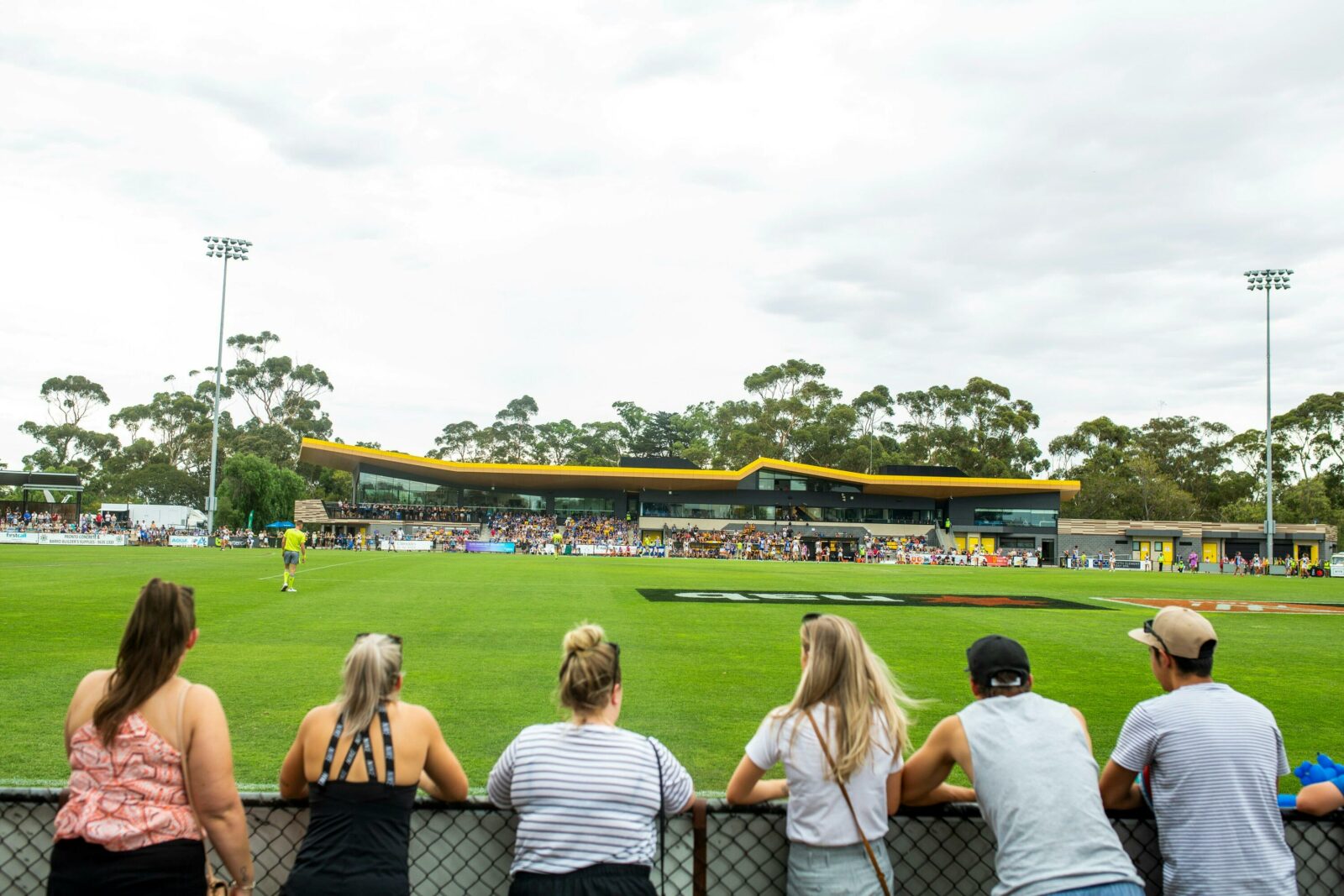 people standing at fence watching football at Chirnside Park