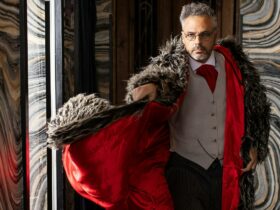 A well dressed man swooshes a fur coat with bright red inner lining.