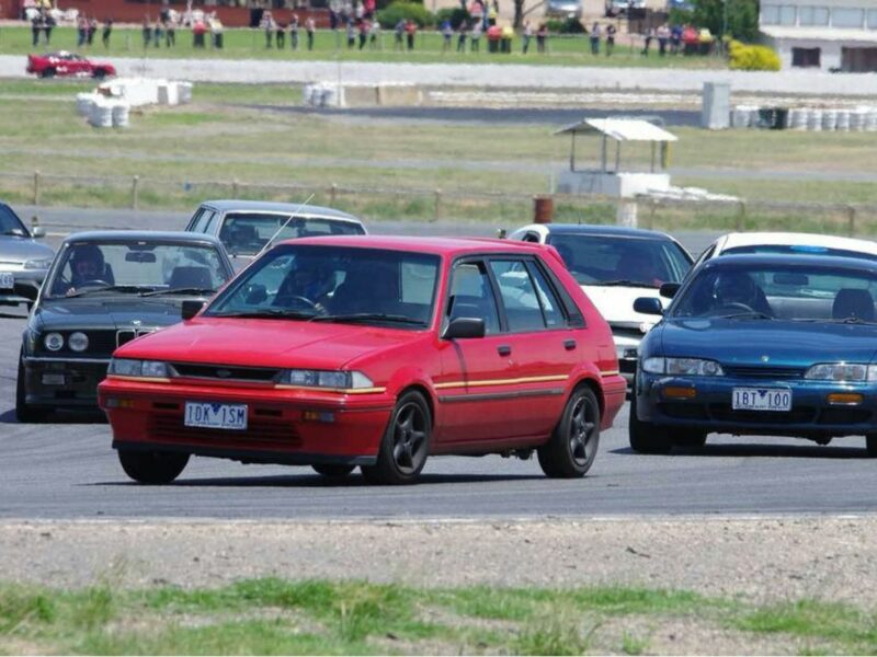 A group of cars on Winton Racetrack with spectators in the background