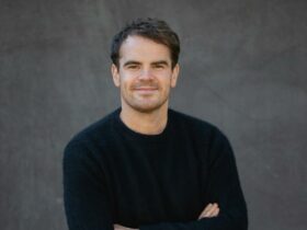 Photo of a man in a black sweater in front of a dark grey background