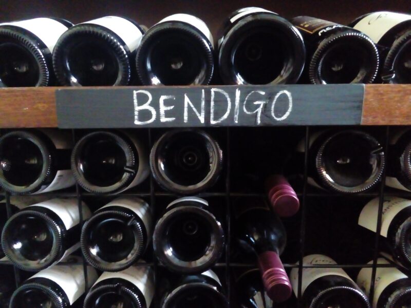 Photo of several wine bottles stacked neatly with the word 'Bendigo' on the front of the shelf