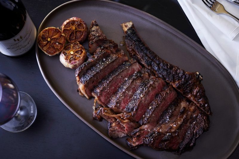 Large, delicious steak on a plate with roast garlic
