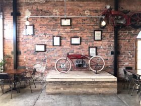 Vintage Motorbike mounted on wooden stage, rustic brick wall behind