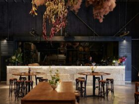 A view of the long stone bar, timber tables with stool seating and a hanging floral installation