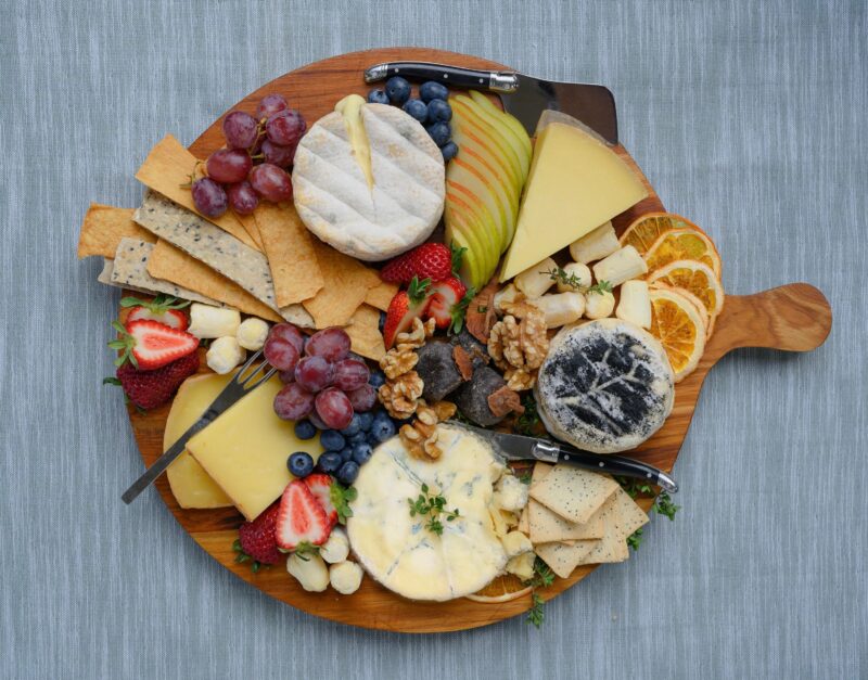 Wooden platter with different cheeses and fruit