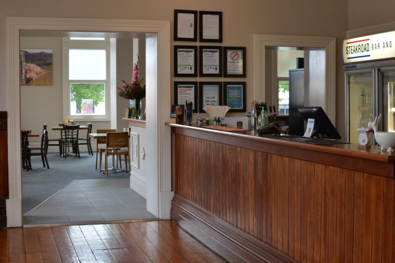 Bar leading into the dining area with a wooden floor, bar and large windows
