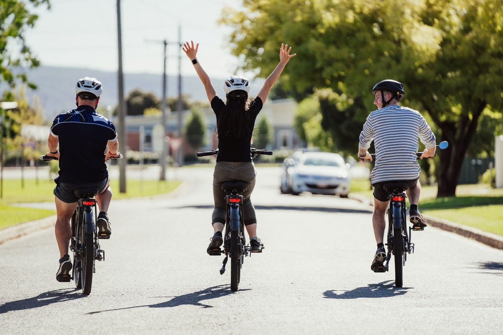 Three people riding bikes down a street