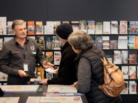 Rick standing in front of a brochure wall, helping two visitors