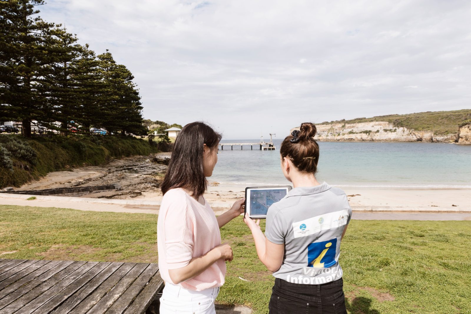 Visitor being shown information on a tablet on the Port Campbell foreshore