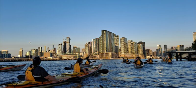 Kayakers on water with city skyline in the background