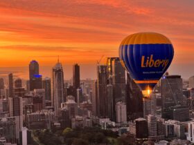 Hot air balloon flying over the City of Melbourne with strong orange sunrise in background
