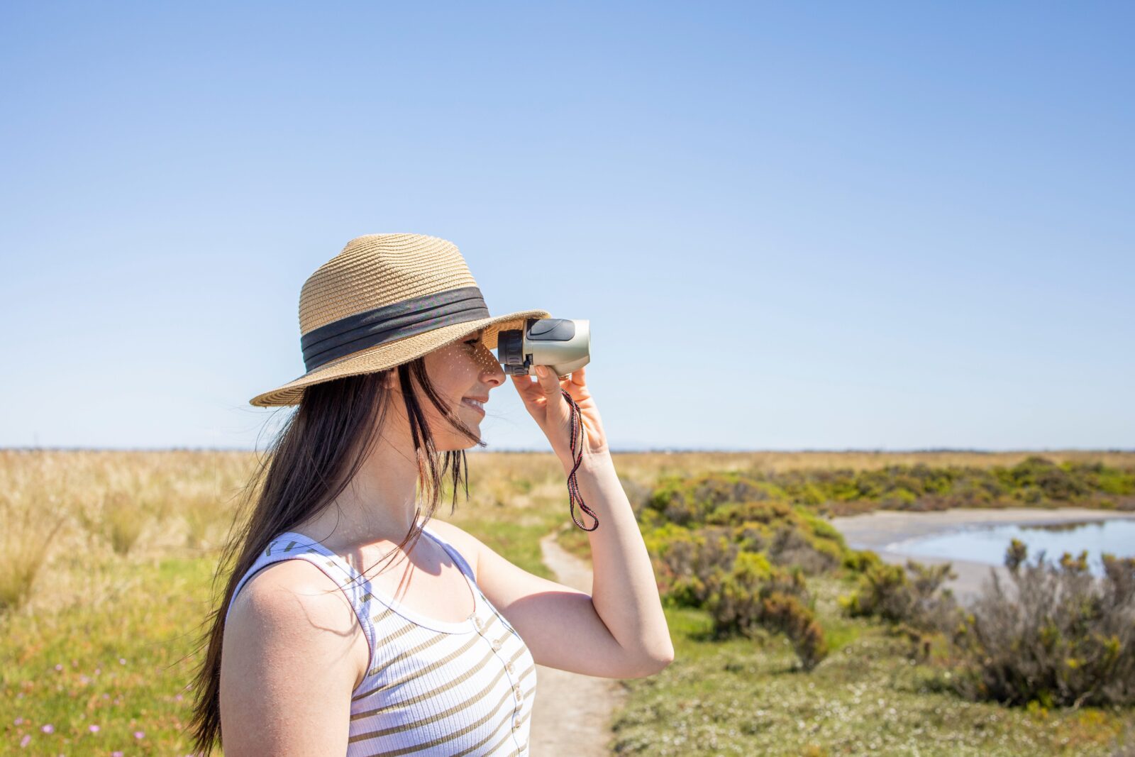 Woman using binoculars at wetlands