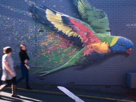 People strolling past parrot mural
