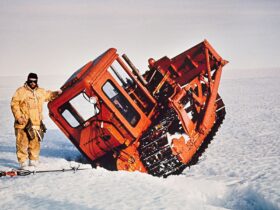 Man stands next to D5 tractor wedged in a crevice in Antarctica