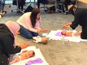 Mothers learn how to massage their babies from a baby massage instructor
