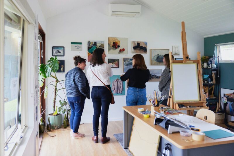 visitors to art studio looking at still life paintings on a wall