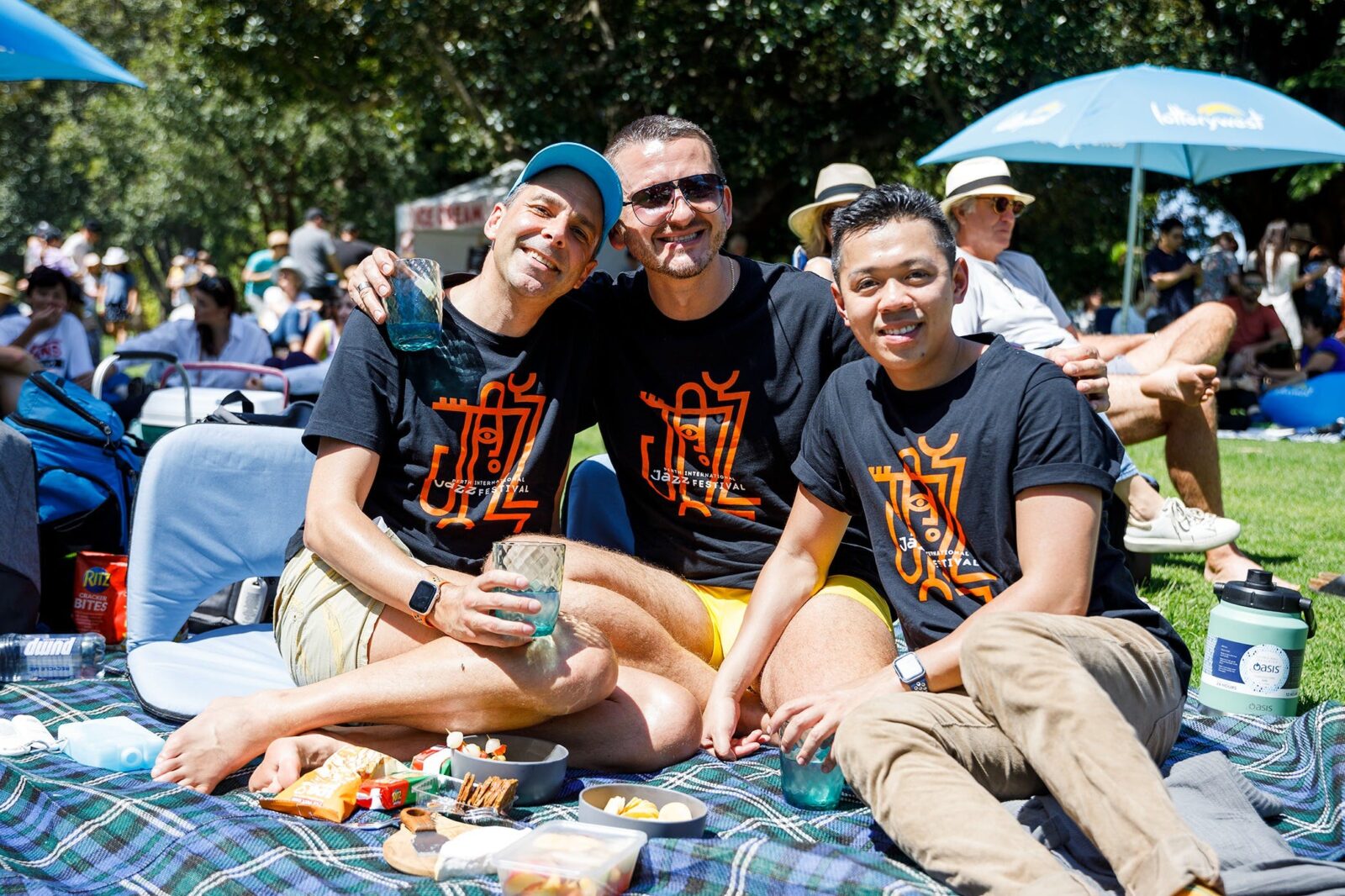 3 audience members enjoying the Jazz Picnic in the Park wearing matching jazz festival t-shirts