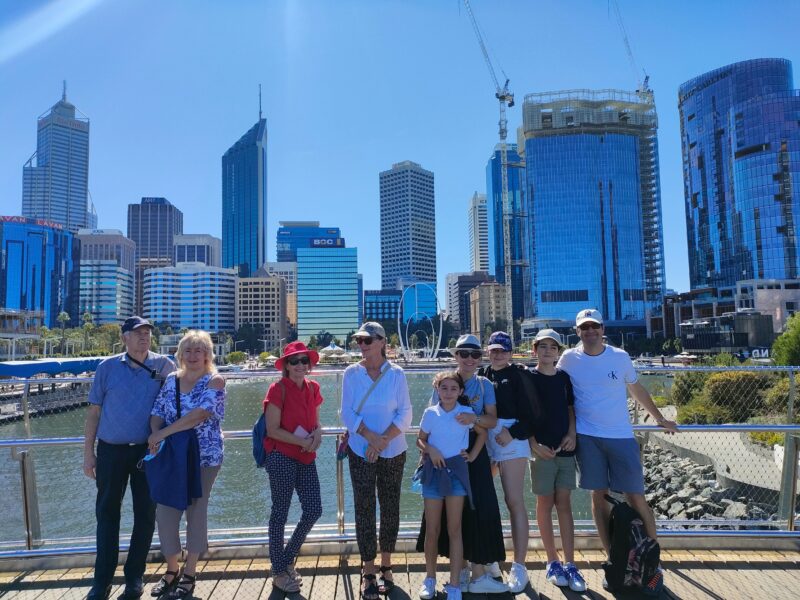 A group of tour guests smiling with Perth's city skyline in the backgroung