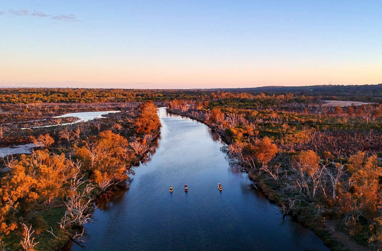 Drone shot of three kayaks on a river.
